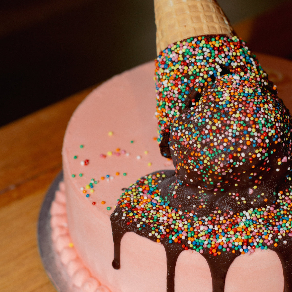 close up of a melting ice cream cone birthday cake highlighting the dripping ice cream-inspired decoration and playful cake finish.