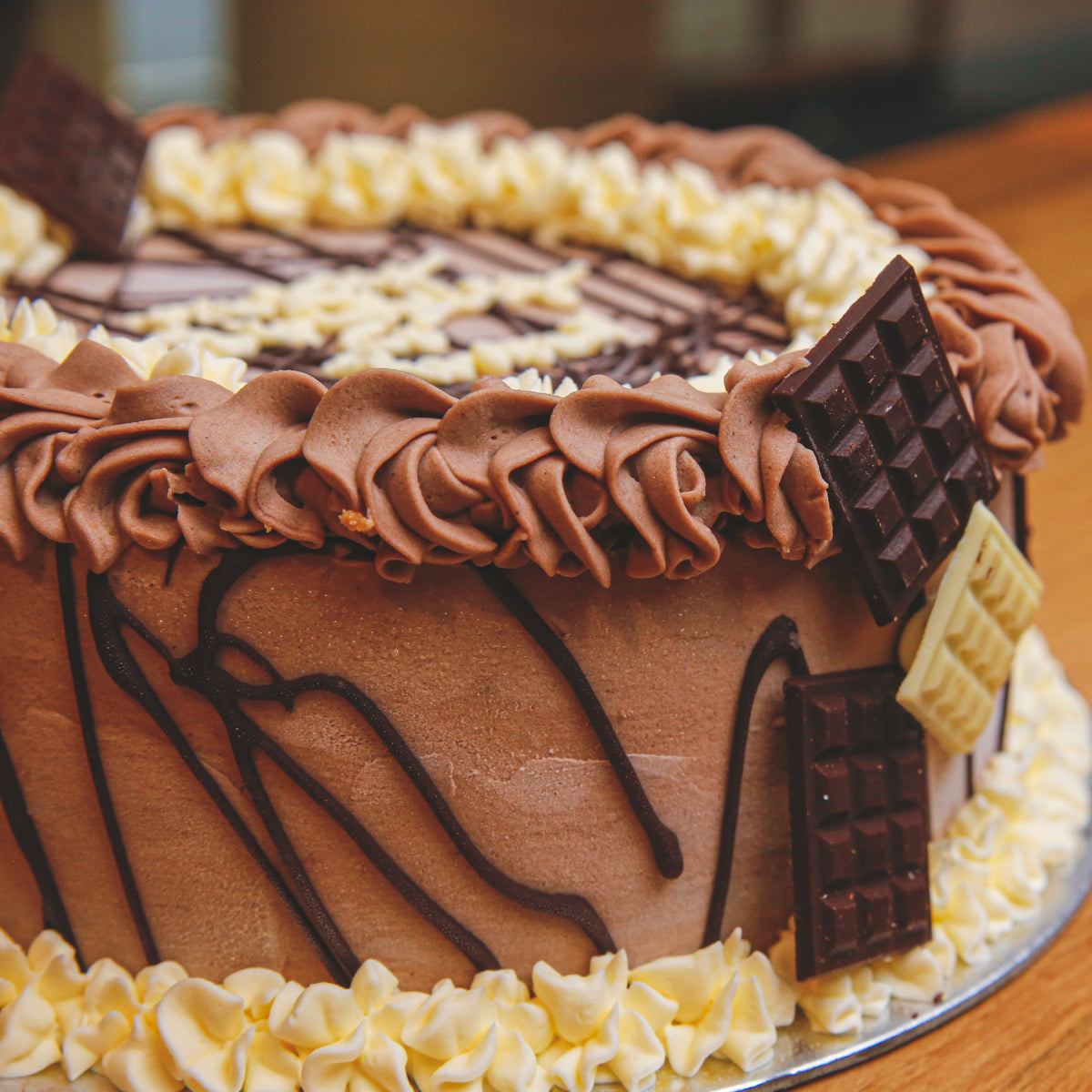 Side view of a chocolate bar birthday cake highlighting its decorative chocolate treats and chocolate-inspired finish.