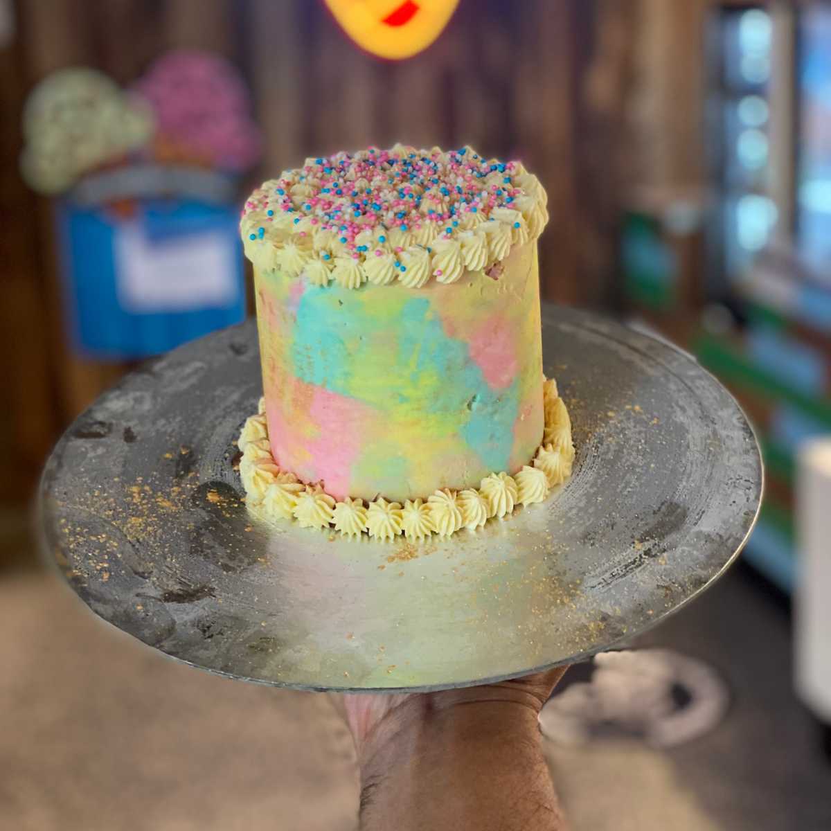 Front view of a tall rainbow confetti cake made with Ben & Jerry's ice cream in Adelaide, showcasing its cheerful multicoloured decorative styling.