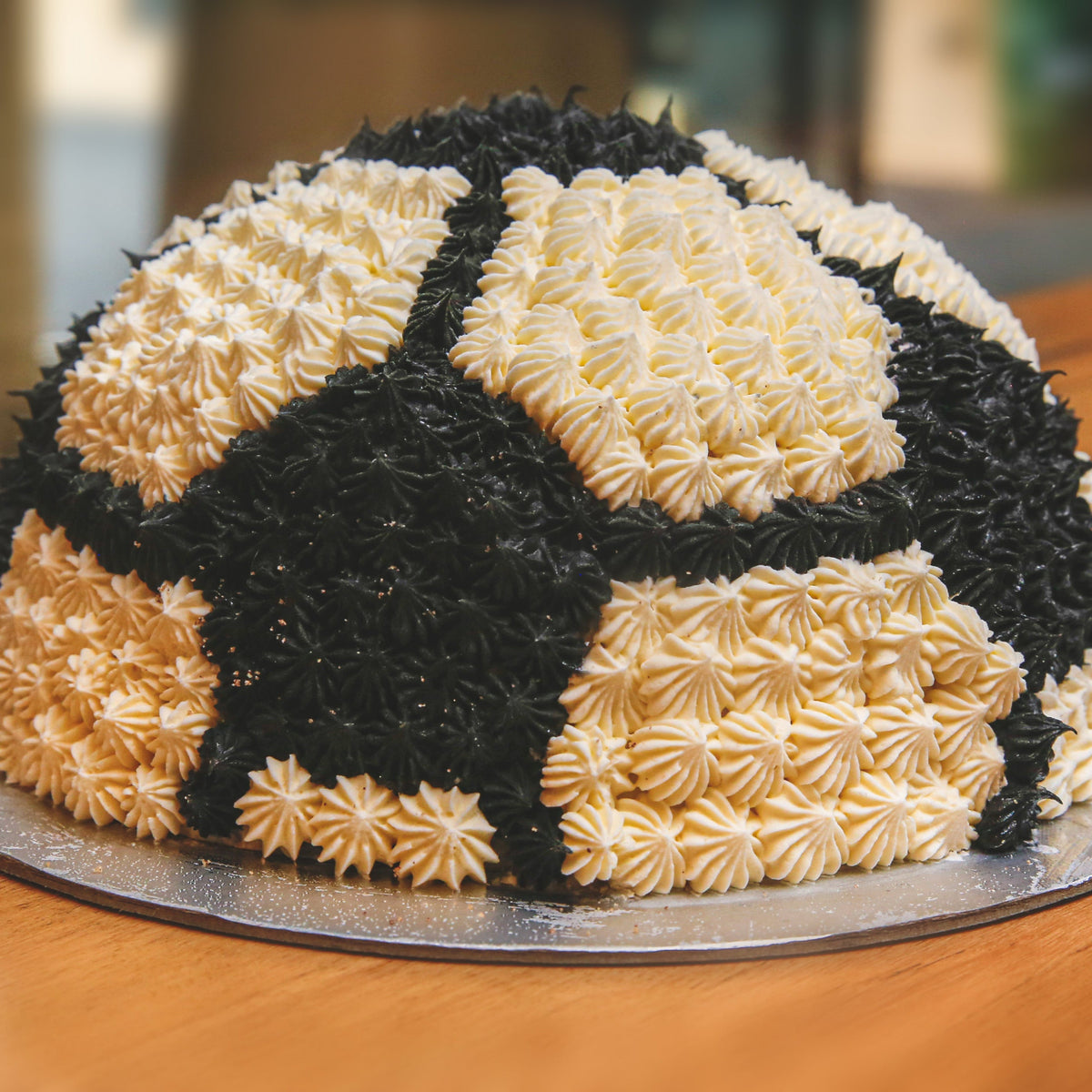 front view of a handcrafted soccer ball ice cream cake highlighting its curved dome structure and black-and-white football-inspired decoration.