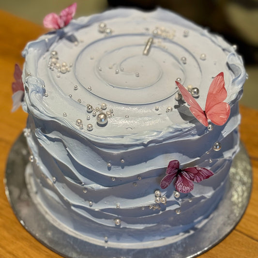 top view of a baby blue and white birthday cake in Adelaide, showcasing its modern wave-effect design and pastel colour palette.