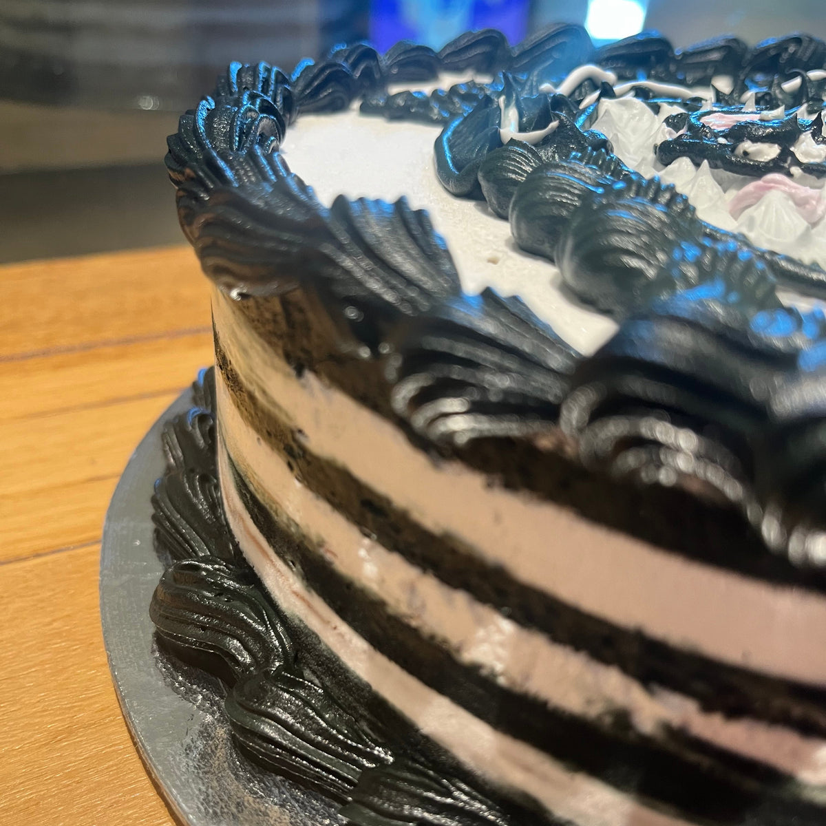 Close-up of Wednesday Addams-inspired decorations on a themed birthday cake handcrafted in Adelaide using Ben & Jerry's ice cream.