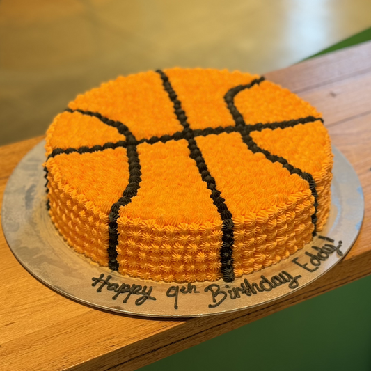Full view of a round basketball birthday cake handcrafted in Adelaide using Ben & Jerry's ice cream, featuring classic orange and black basketball styling.