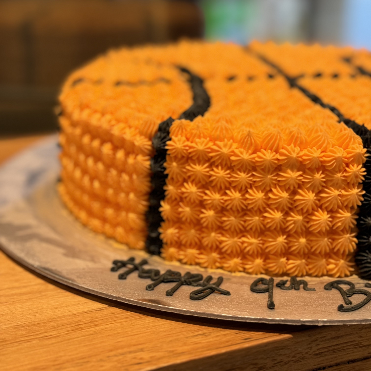 Close-up of the orange and black basketball-inspired decorations on a round birthday cake handcrafted in Adelaide using Ben & Jerry's ice cream.
