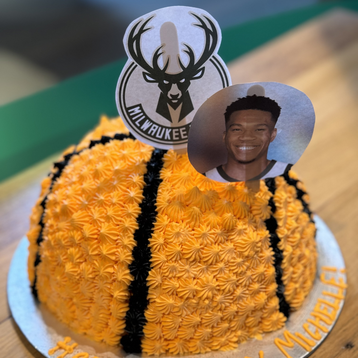top view of a 3D basketball birthday cake made with Ben & Jerry's ice cream in Adelaide, showcasing its curved orange dome and black basketball line detailing.
