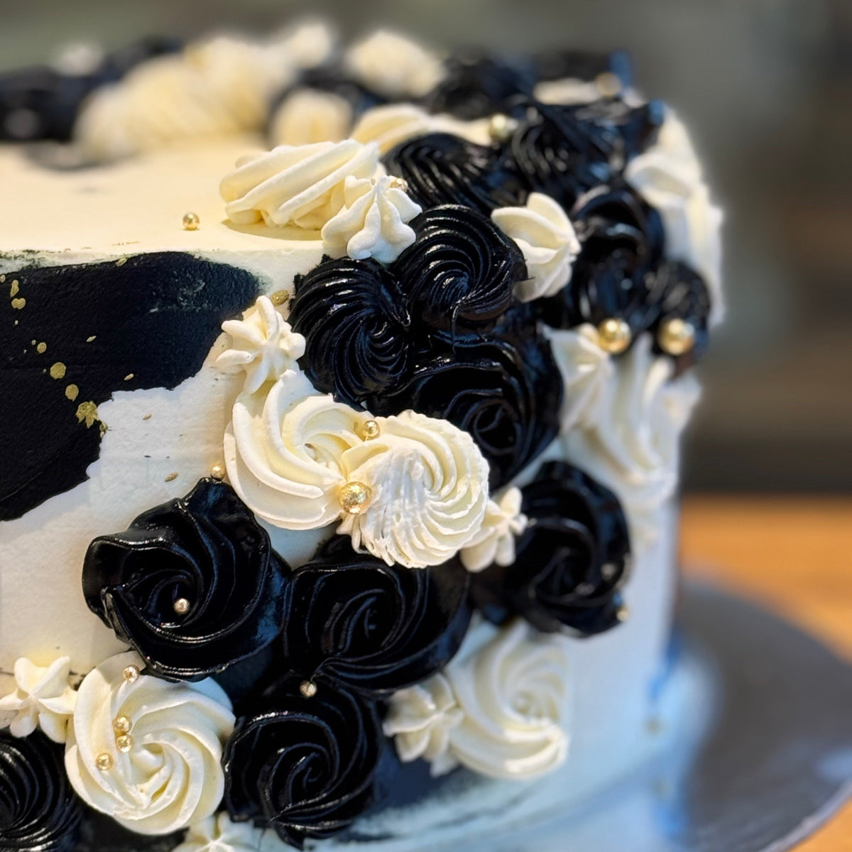 Close-up of the gold accents and flowing decorative details on a black and white mud or sponge cake handcrafted in Adelaide.