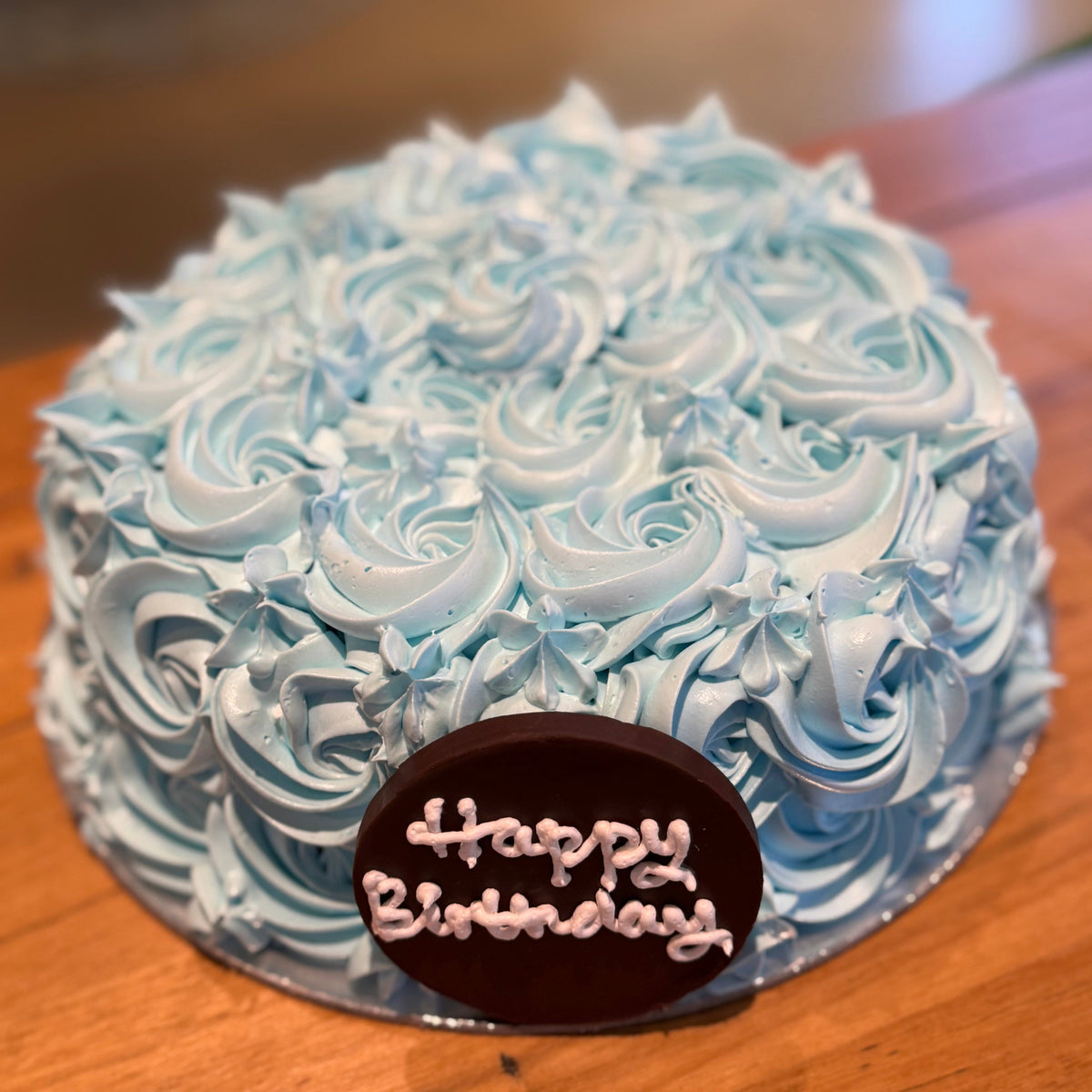 Full view of a blue rosette birthday cake handcrafted in Adelaide using Ben & Jerry's ice cream, featuring elegant floral piping.