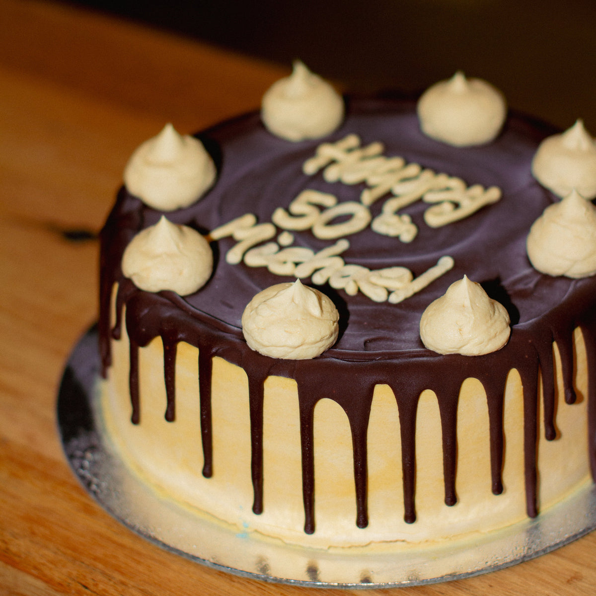 side view of a caramel fudge birthday ice cream cake showcasing its decorative caramel and chocolate fudge drizzle.