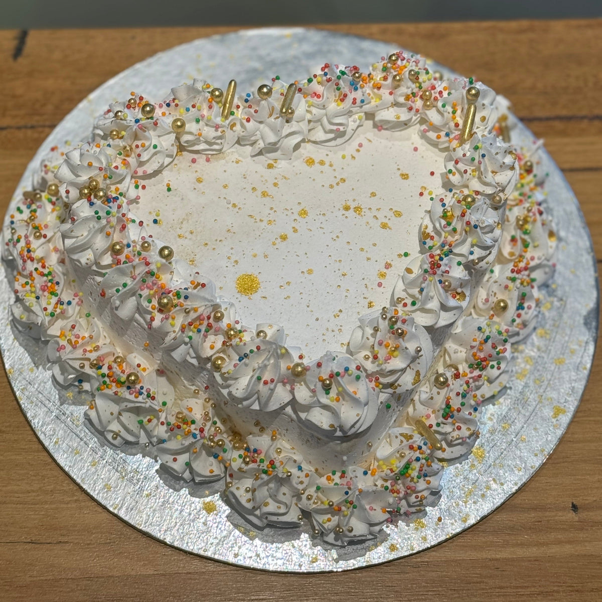 top view of a handcrafted gold dust heart ice cream cake in Adelaide made using Ben & Jerry's ice cream, highlighting its glamorous finish.