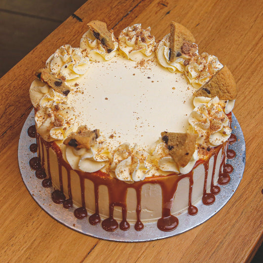 Full view of a choc chip cookie caramel drip ice cream cake featuring cookie-inspired decorations and a rich caramel drip finish.