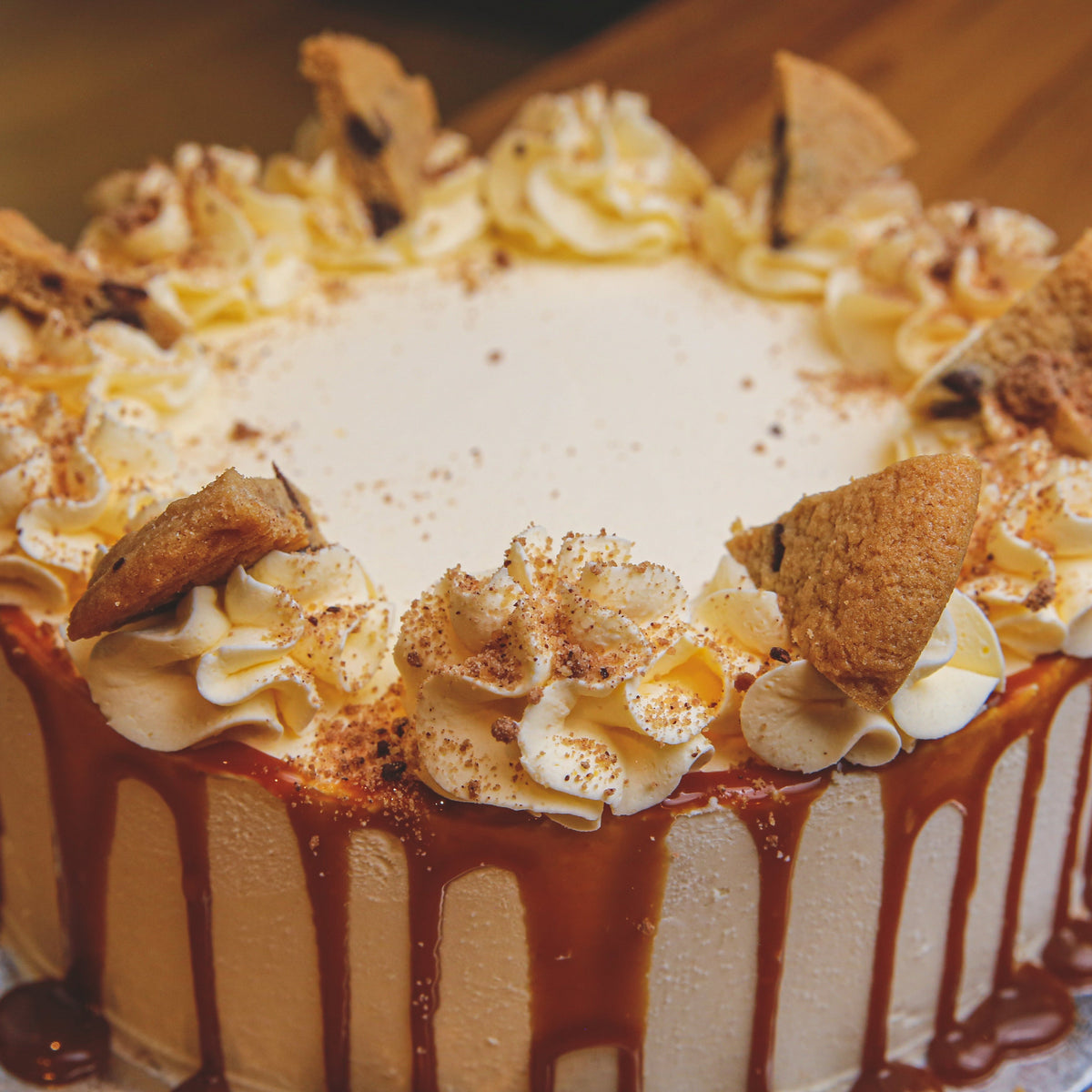 Close-up view of chocolate chip cookie decorations and caramel drip detailing on a handcrafted birthday ice cream cake.