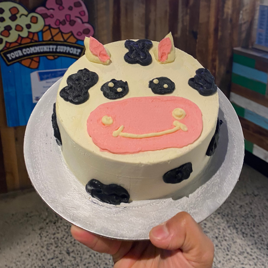 Full view of an adorable cow-themed birthday cake handcrafted in Adelaide using Ben & Jerry's ice cream, designed for a playful farmyard celebration.