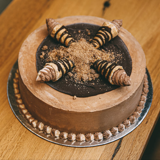 Full view of a handcrafted ice cream cone birthday cake featuring decorative cones and a chocolate ganache finish.