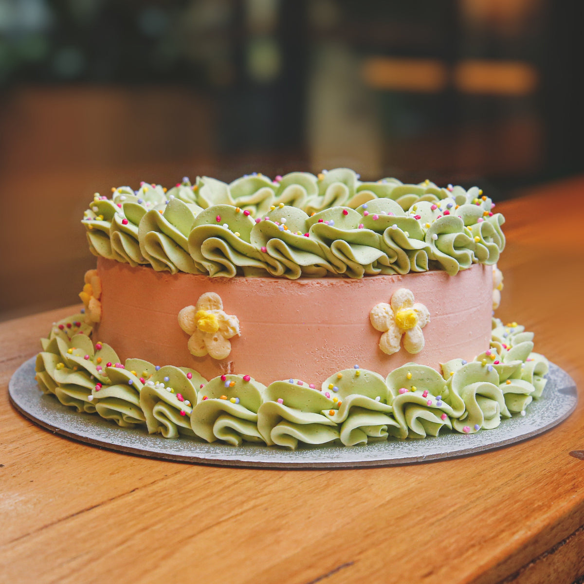 Front view of a daisy-themed ice cream cake showcasing its charming flower decorations and birthday cake presentation.
