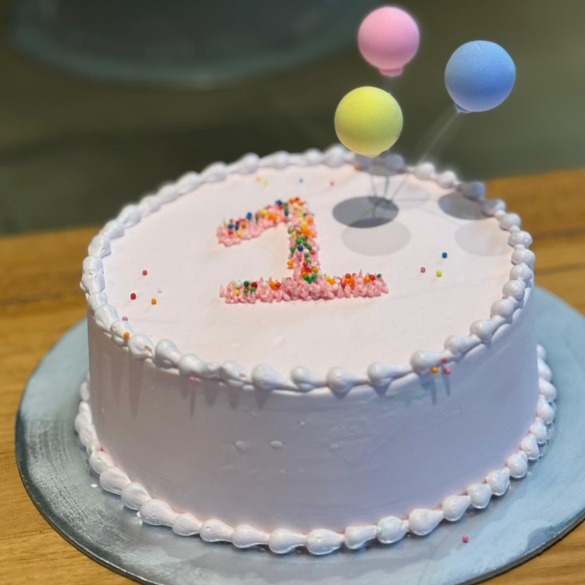 Full view of a first birthday balloon cake handcrafted in Adelaide using Ben & Jerry's ice cream, featuring cheerful balloon-inspired decorations.