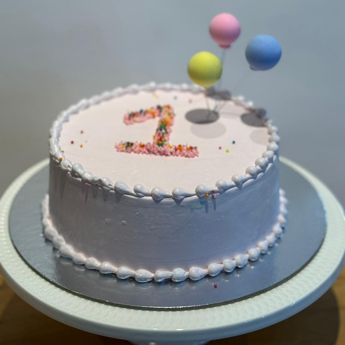 front view of balloon-inspired decorations on a first birthday cake handcrafted with Ben & Jerry's ice cream in Adelaide.