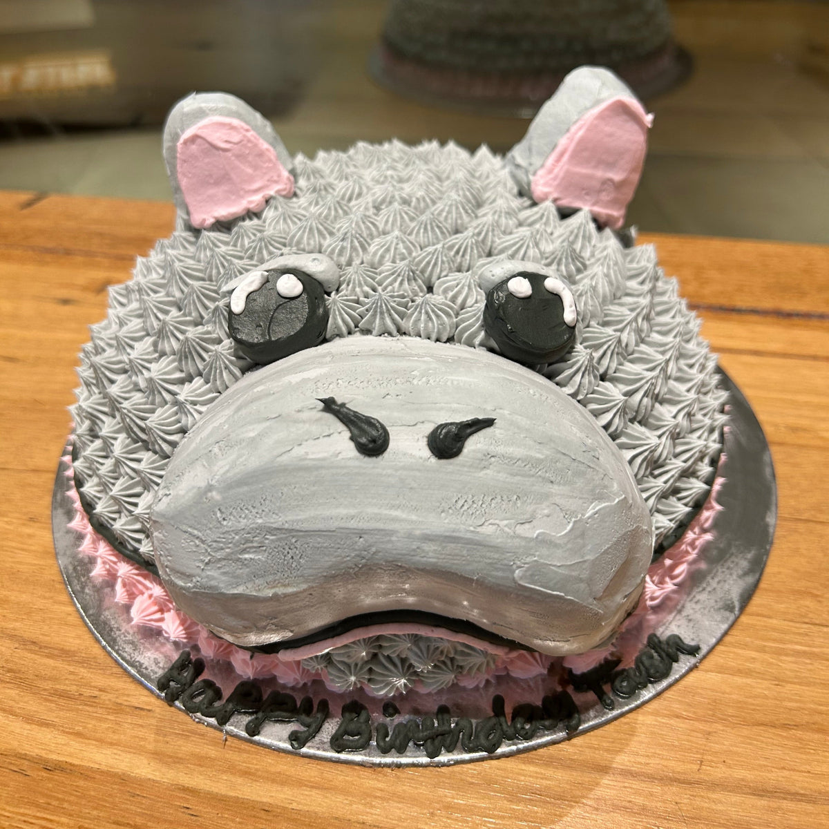 front view of the cute hippopotamus-inspired facial decorations on a dome cake handcrafted in Adelaide using Ben & Jerry's ice cream.
