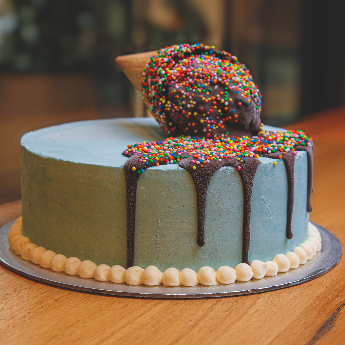 Front view of a handcrafted melting cone ice cream cake showcasing the decorative ice cream cone and melting effect.