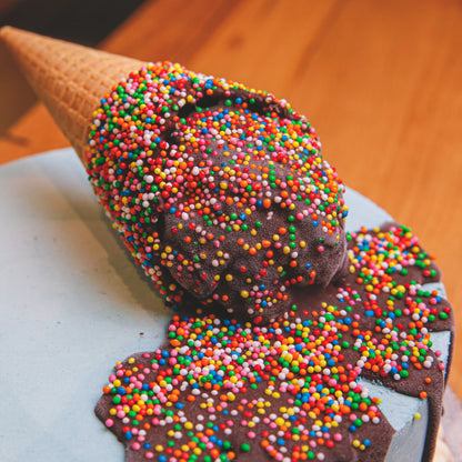 close up of a melting ice cream cone birthday cake highlighting the dripping ice cream-inspired decoration and playful cake finish.