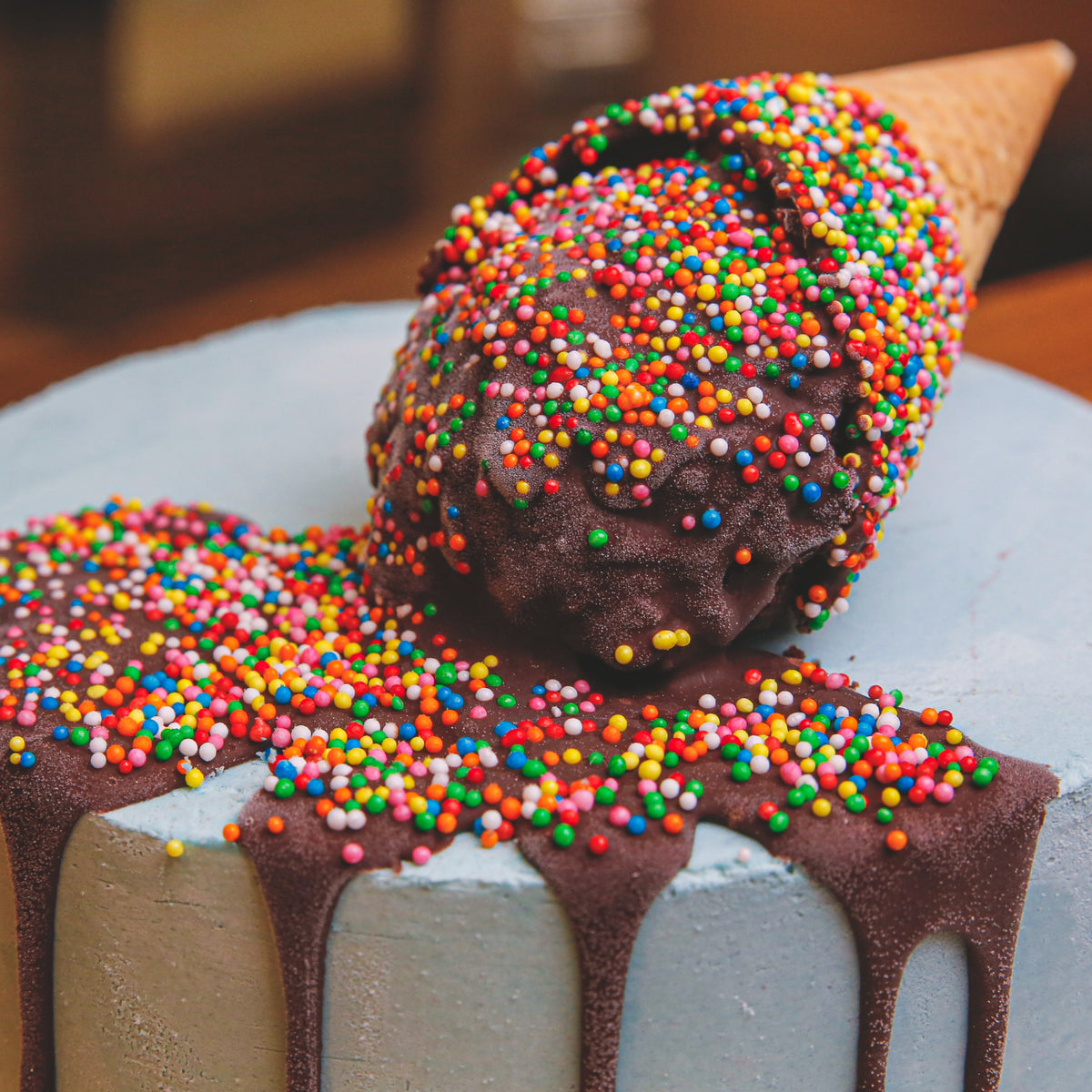 Close-up view of the melting cone birthday cake highlighting its ice cream scoop-inspired topper and realistic melting decoration.