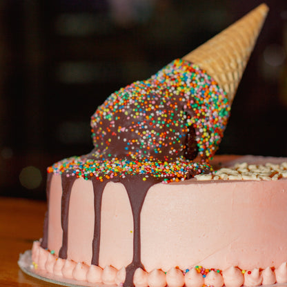 close up of a handcrafted melting cone ice cream cake showcasing the decorative ice cream cone and melting effect.