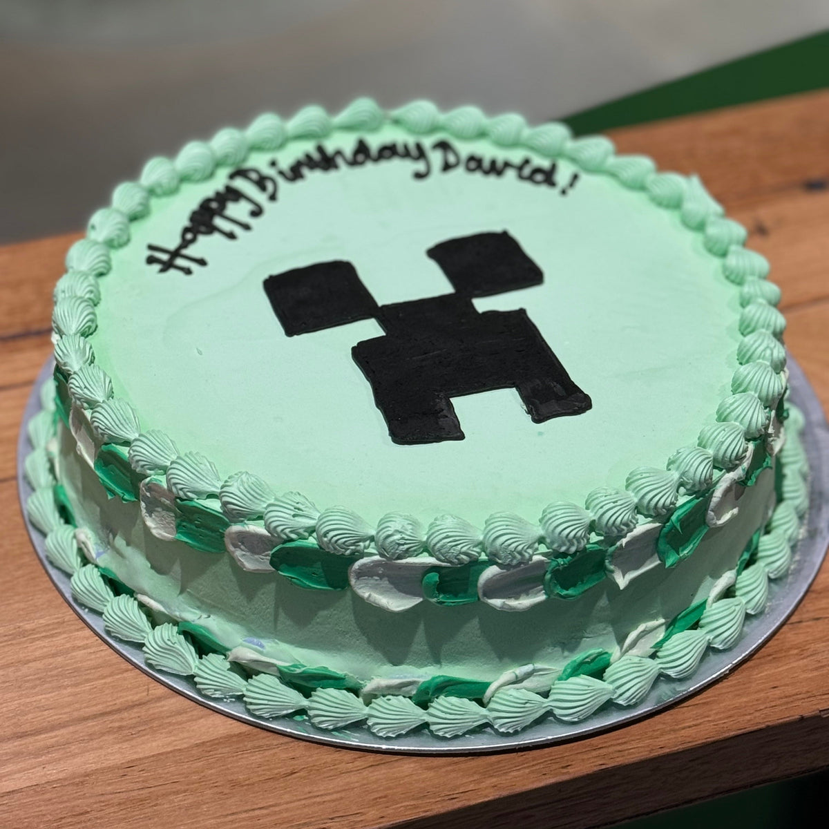 side view of a Minecraft Creeper ice cream cake showcasing the recognisable green Creeper face and block-inspired birthday design.