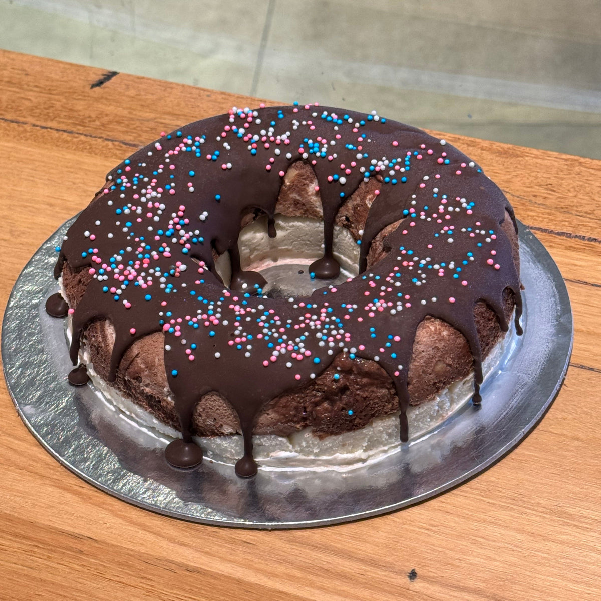 Full view of a naked-style donut birthday cake handcrafted in Adelaide using Ben & Jerry's ice cream, featuring playful donut decorations.