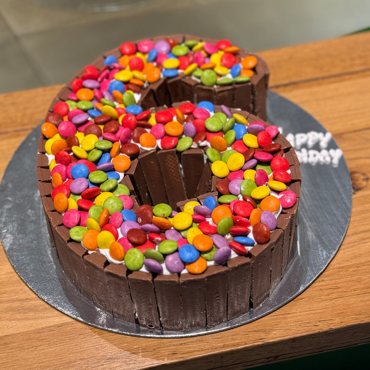 Full view of a number six birthday cake handcrafted in Adelaide using Ben & Jerry's ice cream, decorated with Kit Kat chocolate and colourful Smarties.