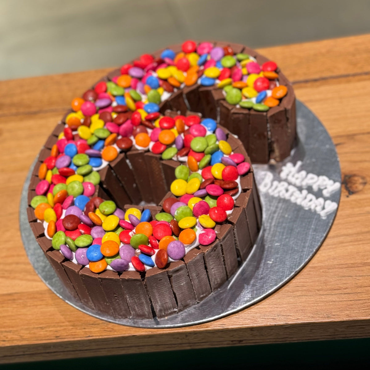 side view of a number 6 birthday cake made with Ben & Jerry's ice cream in Adelaide, showcasing its Kit Kat and Smarties decorations.