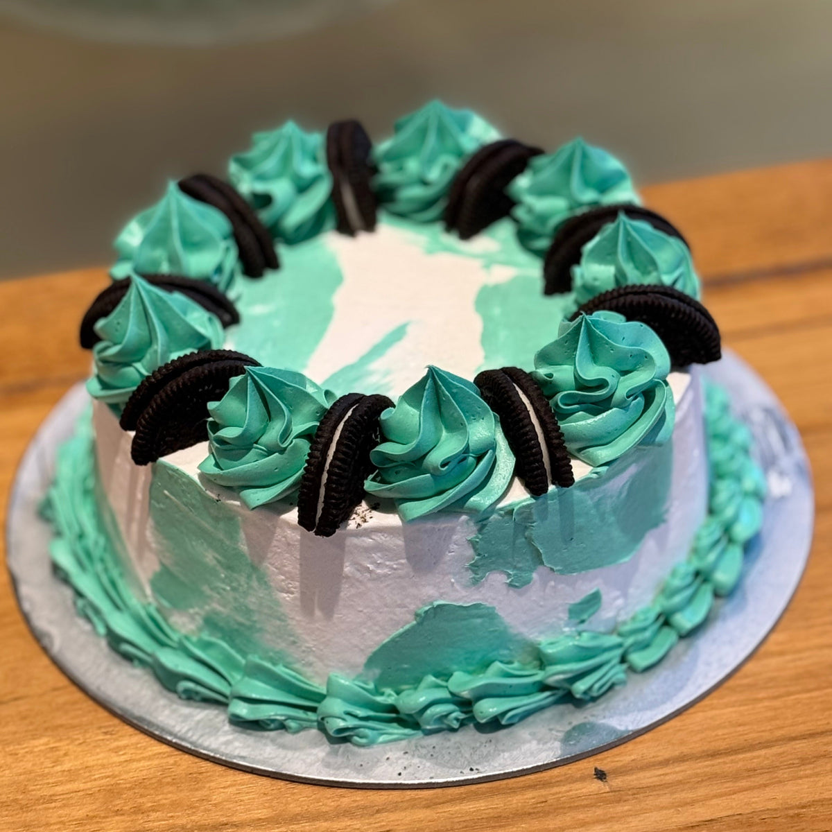 Full view of a green and aqua Oreo drip ice cream cake featuring decorative drips and Oreo cookie-inspired details for birthday celebrations.