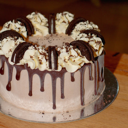 front view of a handcrafted chocolate Oreo ice cream cake highlighting the flowing chocolate drip design and decorative cookie accents.
