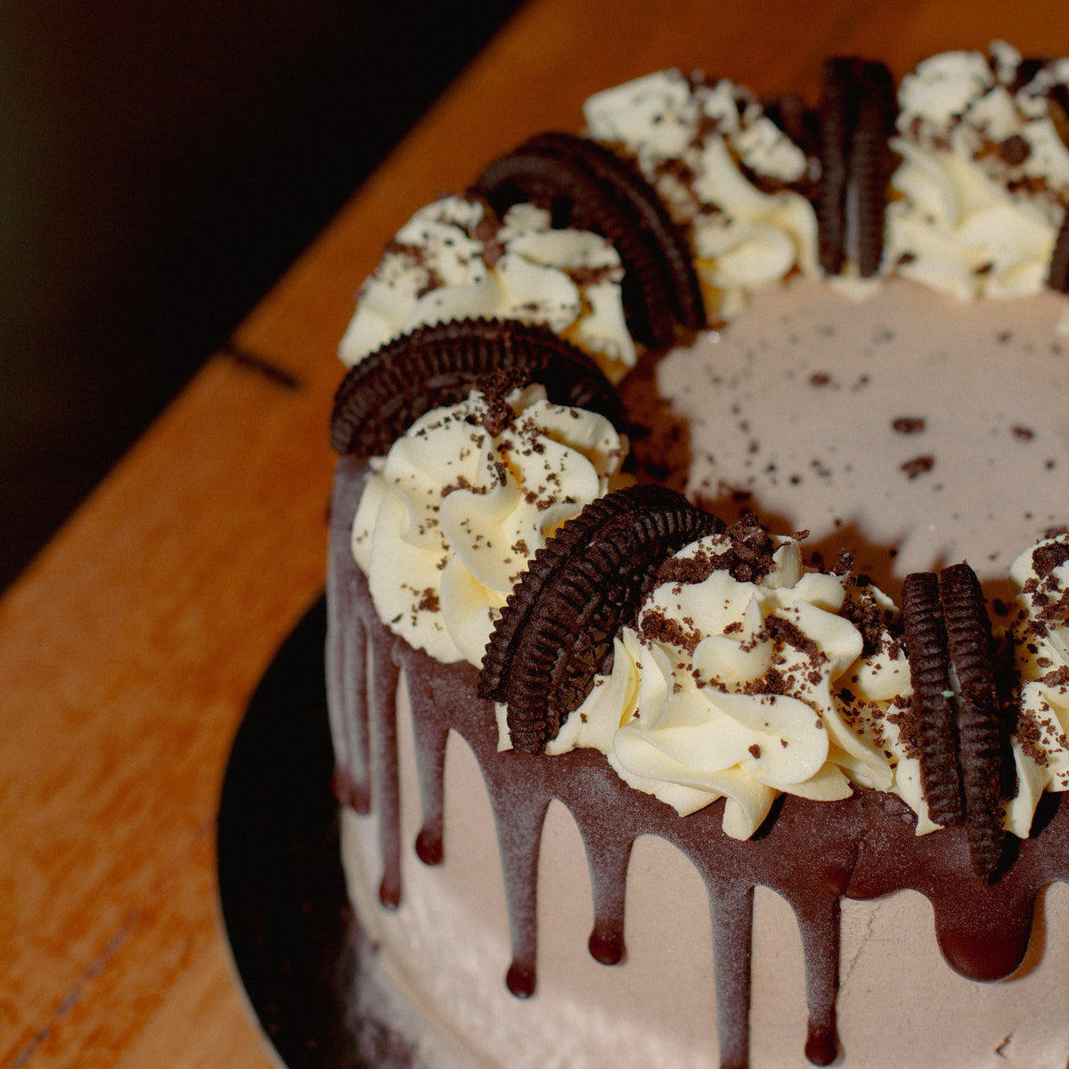 close up of an Oreo chocolate birthday ice cream cake showcasing its decorative chocolate drip finish and Oreo cookie toppings.