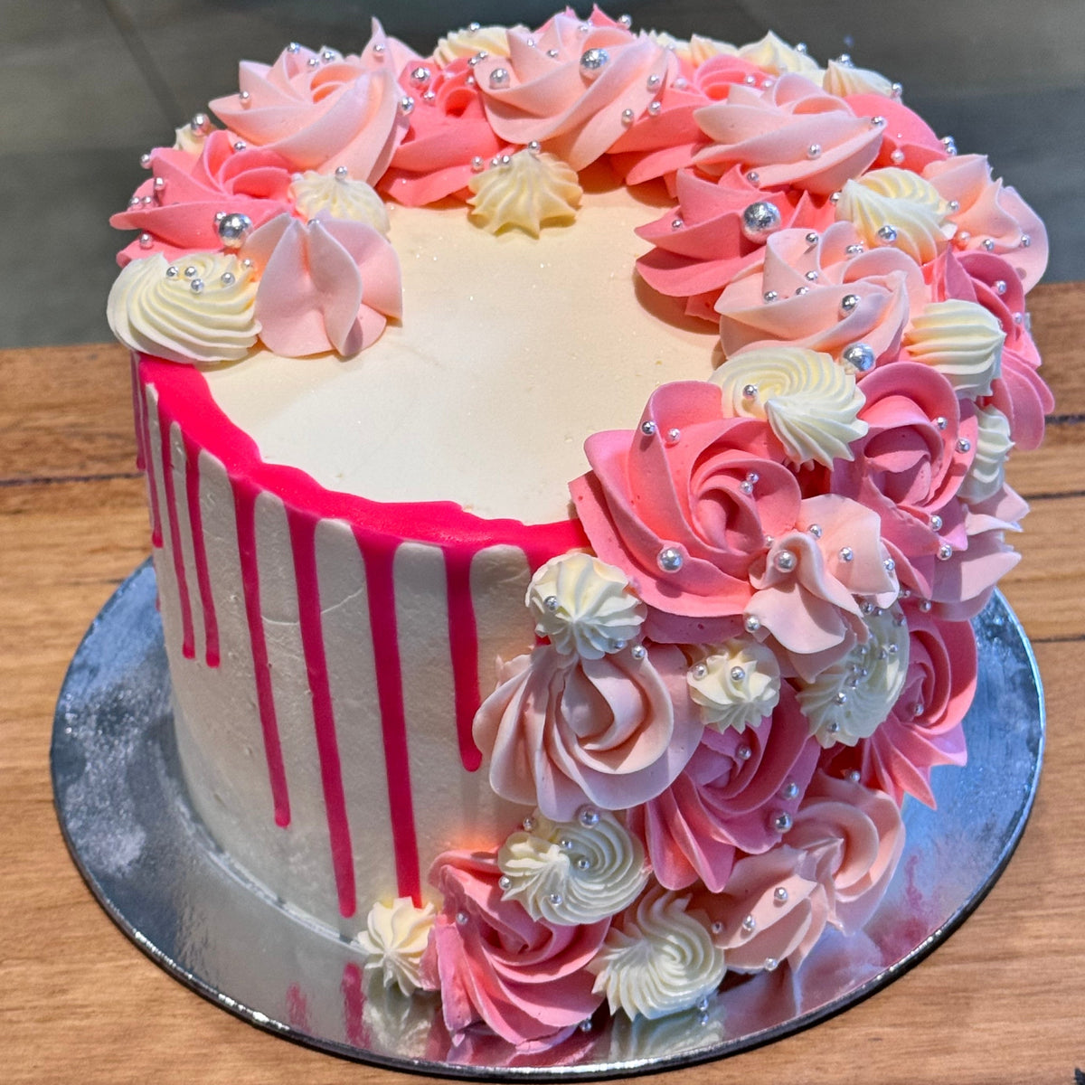 Full view of a pink and white cascading mud or sponge cake handcrafted in Adelaide, featuring elegant silver pearl decorations.