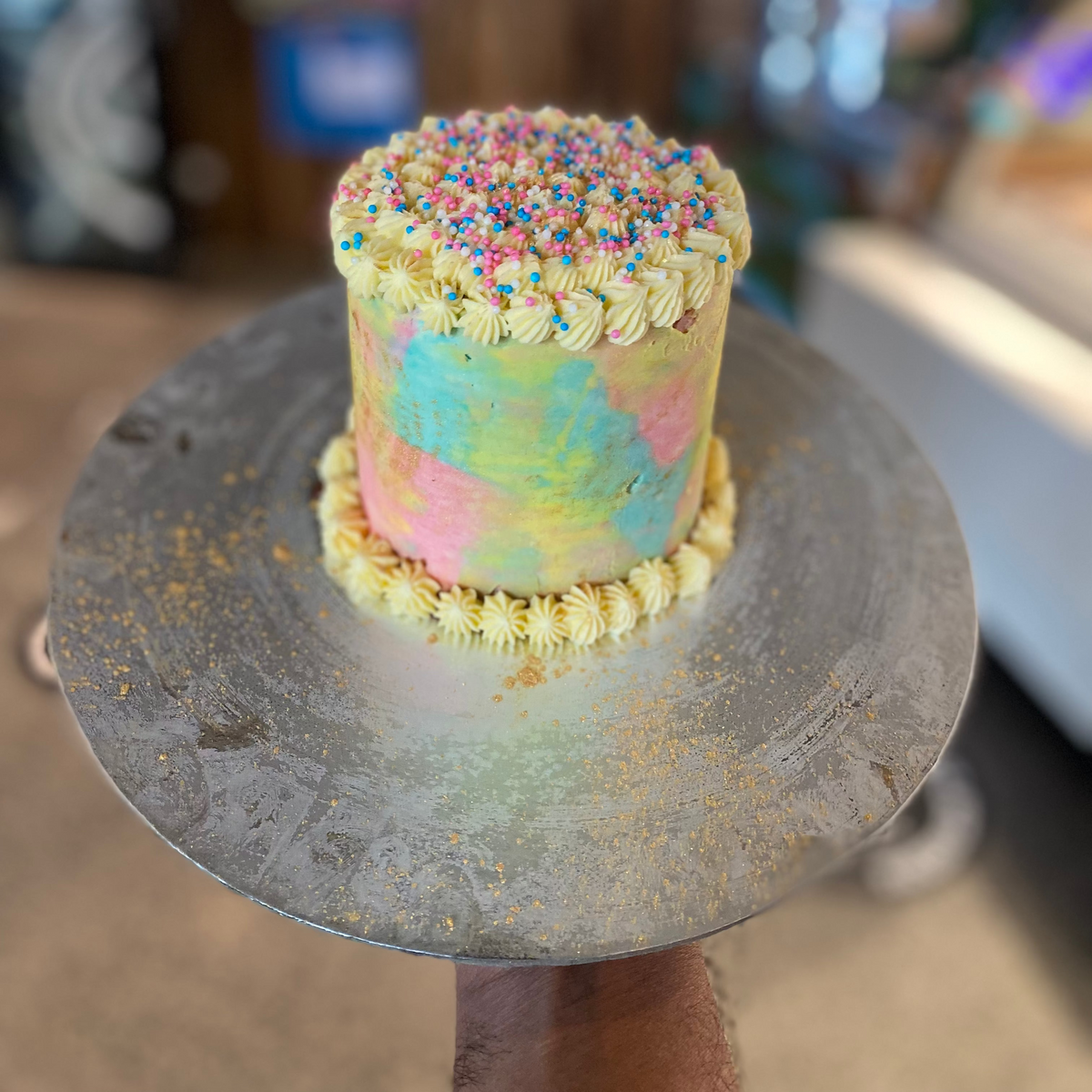 Full view of a tall rainbow confetti birthday cake handcrafted in Adelaide using Ben & Jerry's ice cream, featuring colourful party-inspired decorations.