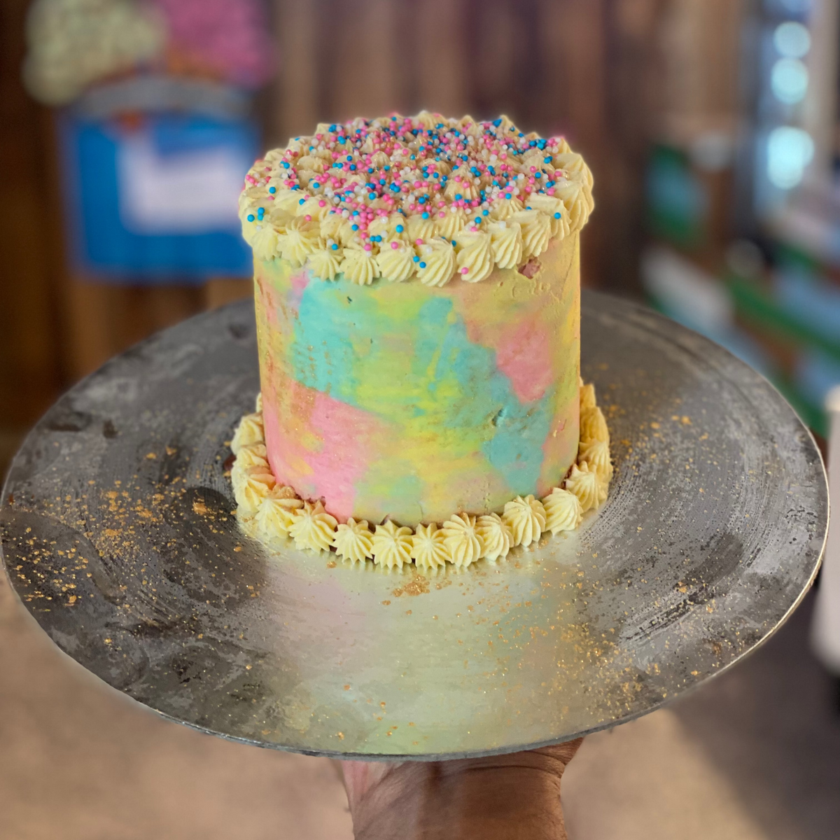 front view of a handcrafted rainbow confetti ice cream cake made using Ben & Jerry's ice cream in Adelaide, highlighting its impressive height and colourful design.