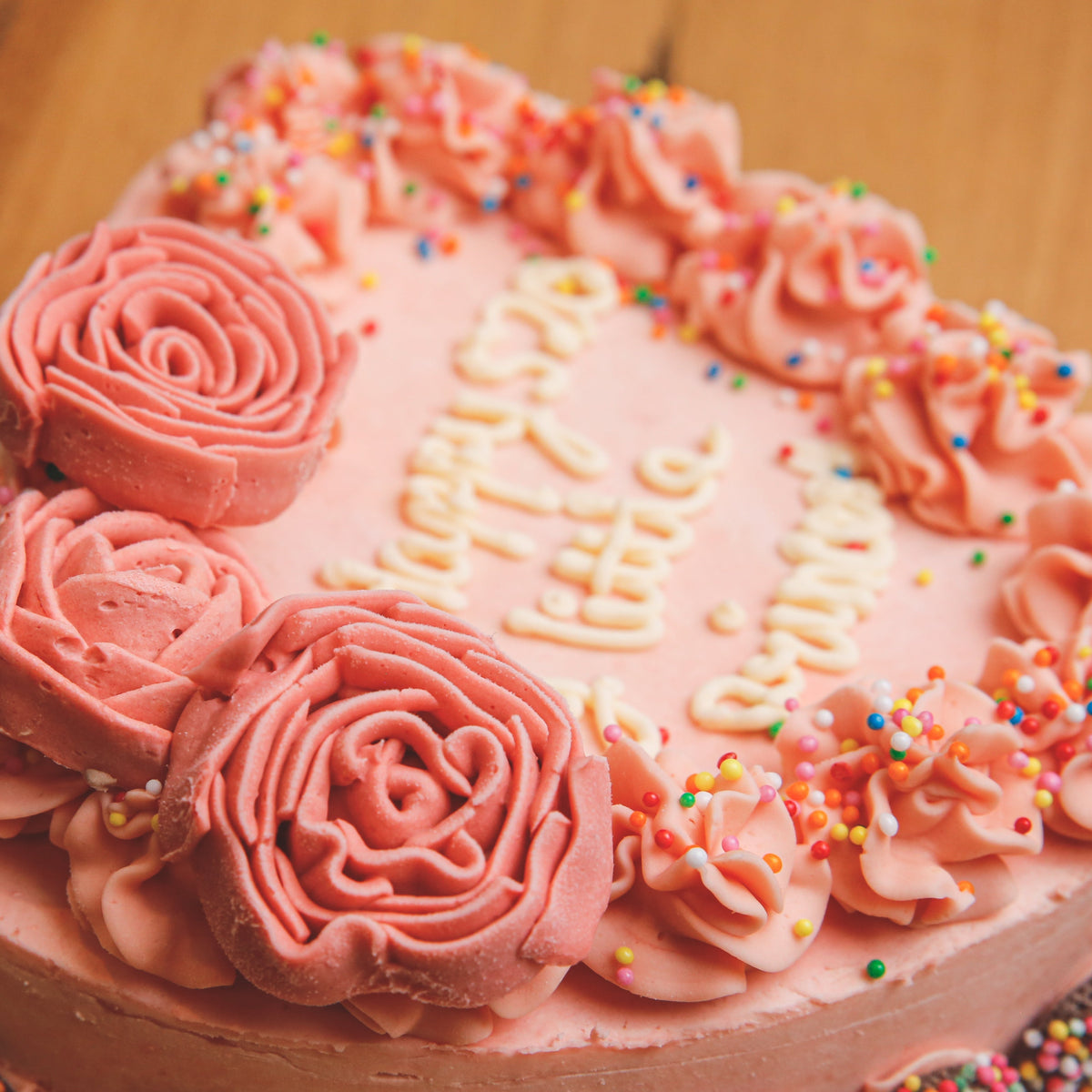 Close-up view of delicate rose-inspired decorations on a handcrafted heart-shaped birthday ice cream cake.