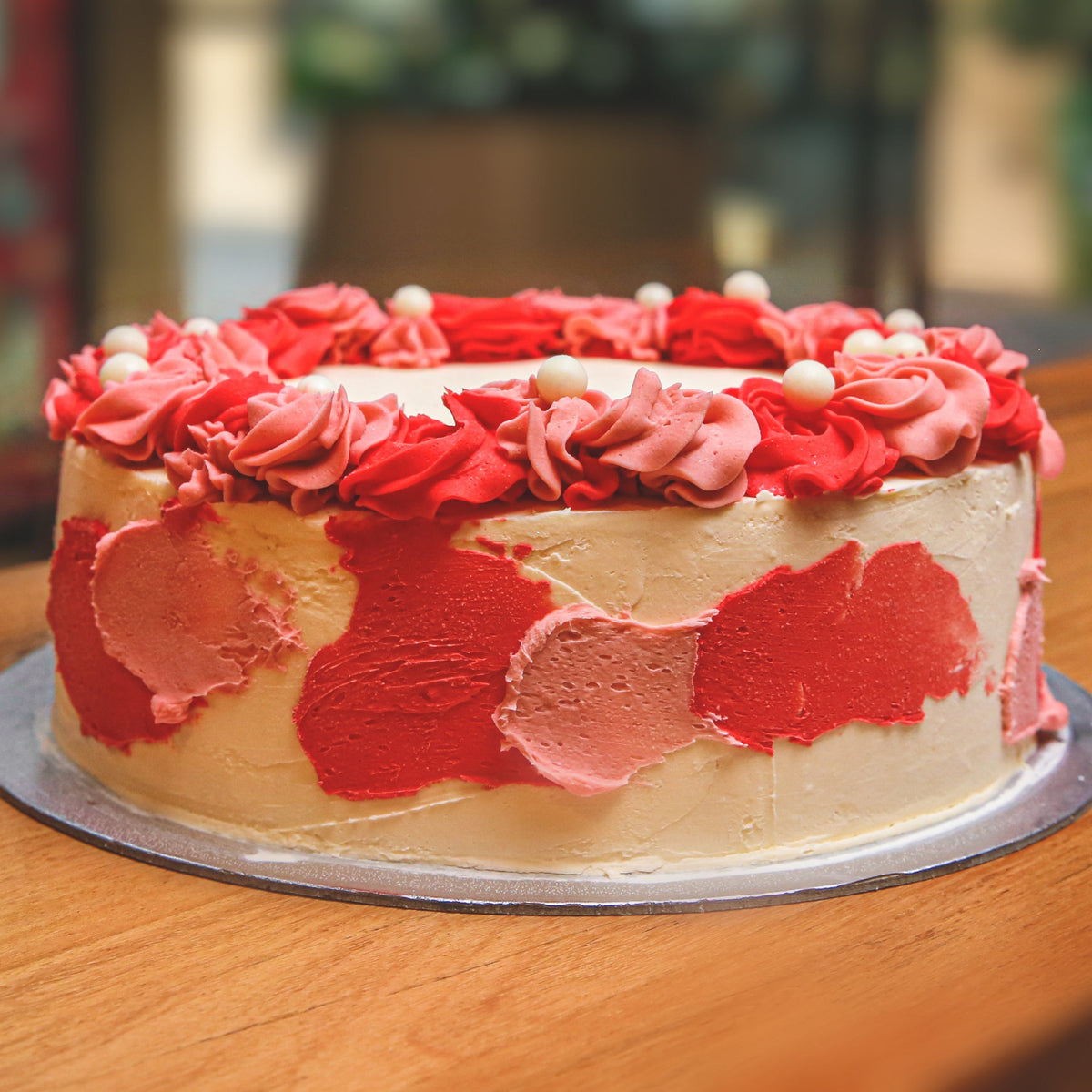Front view of a handcrafted floral ice cream cake showcasing romantic roses and decorative pearl details.
