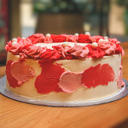 Front view of a handcrafted floral ice cream cake showcasing romantic roses and decorative pearl details.