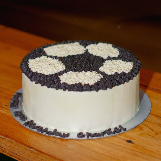 Full view of a round soccer ball birthday ice cream cake featuring football-inspired decorations for a sports-themed celebration.