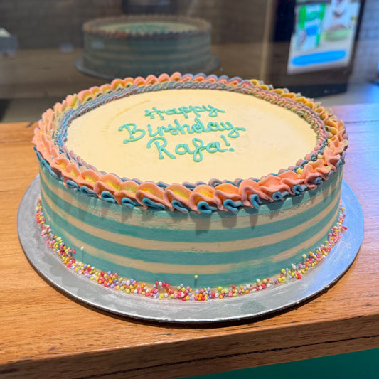 Front view of a handcrafted rainbow ice cream cake showcasing its bright striped design and playful birthday styling.