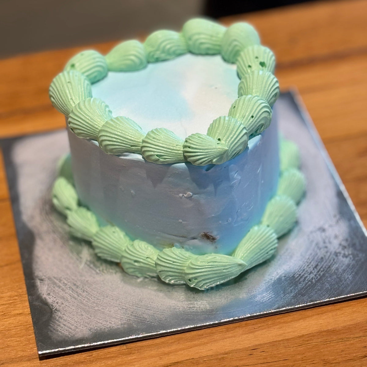 Full view of a green and blue vintage heart cake handcrafted in Adelaide using Ben & Jerry's ice cream, featuring contrasting decorative piping.