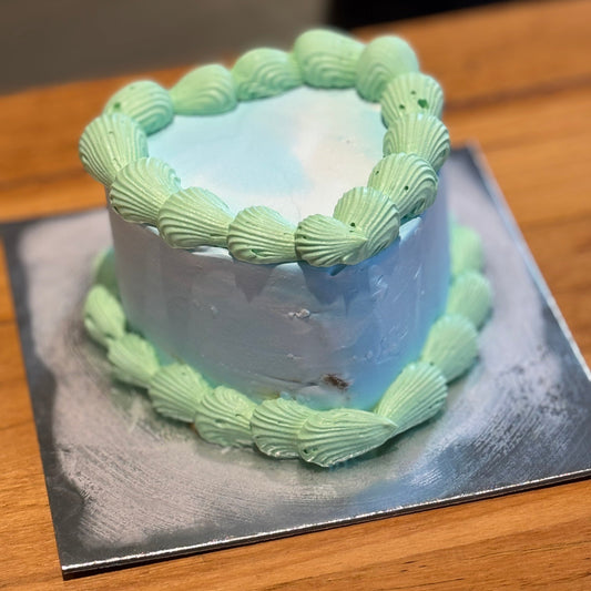 Full view of a green and blue vintage heart cake handcrafted in Adelaide using Ben & Jerry's ice cream, featuring contrasting decorative piping.