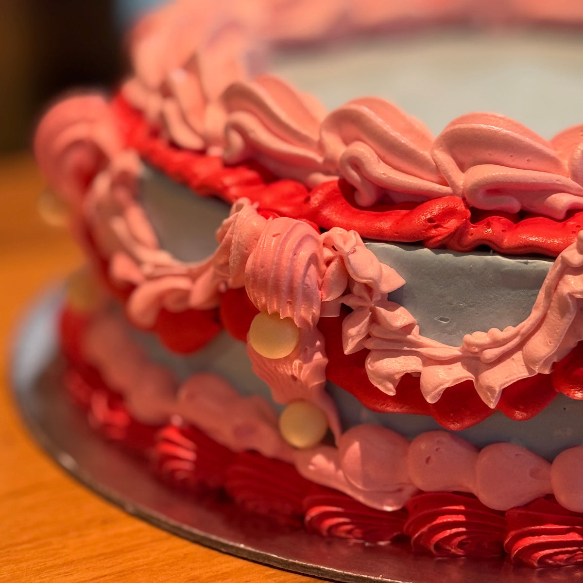 close up of a colourful vintage cake made with Ben & Jerry's ice cream in Adelaide, showcasing contrasting decorative piping and pearl details.