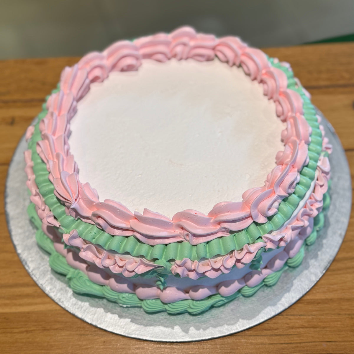 top view of a vintage ice cream cake handcrafted in Adelaide using Ben & Jerry's ice cream, highlighting its white base and soft pink accents.