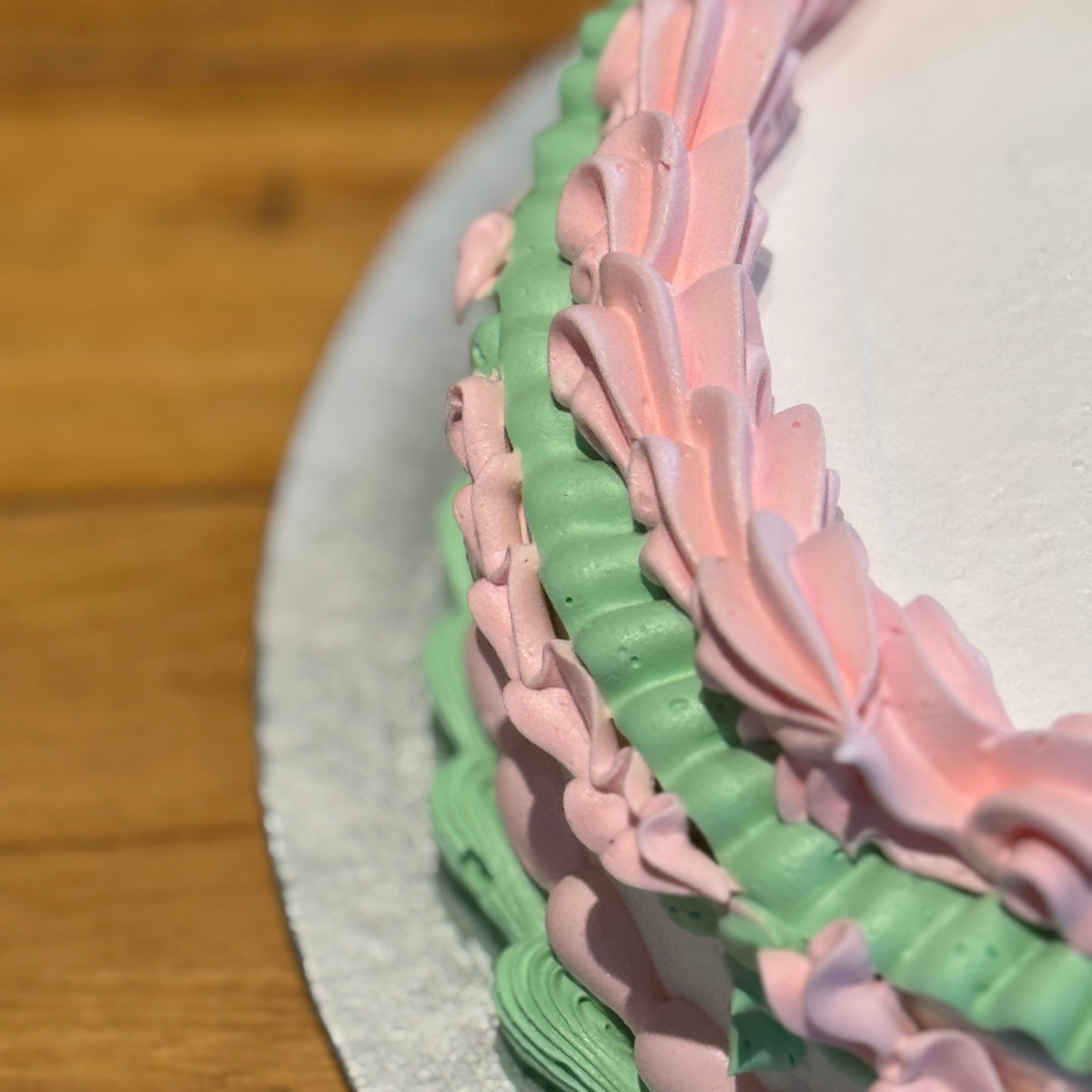 Close-up of delicate baby pink decorative piping on a white vintage cake made in Adelaide using Ben & Jerry's ice cream.