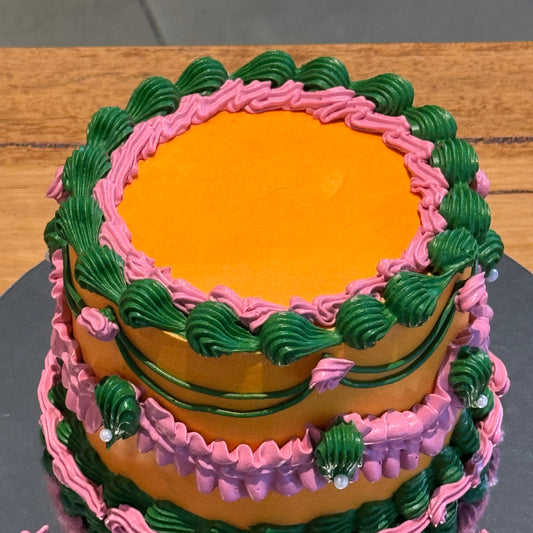 top view of a green, orange and pink vintage cake in Adelaide, showcasing its bright colour combination and decorative piped borders.
