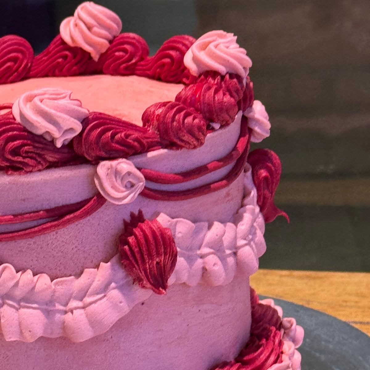close up of a handcrafted vintage celebration cake in Adelaide, highlighting its contrasting red and pink decorations.
