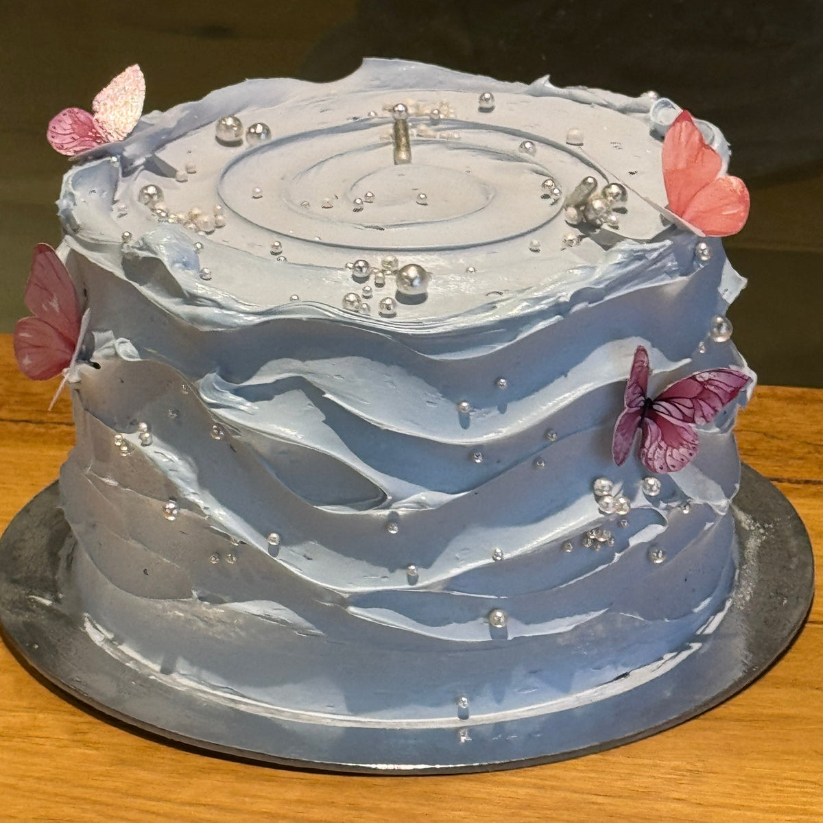 Full view of a baby blue and white wave-effect mud or sponge cake in Adelaide, featuring elegant flowing decorations for birthdays and baby showers.