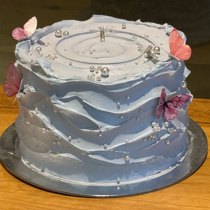 Full view of a baby blue and white wave-effect mud or sponge cake in Adelaide, featuring elegant flowing decorations for birthdays and baby showers.