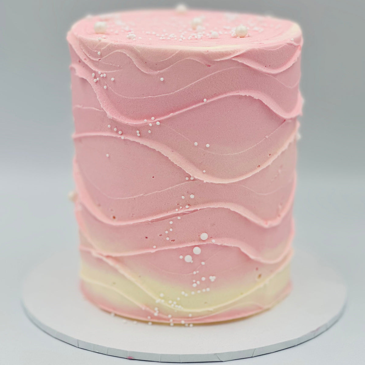 Full view of a baby pink and white wave-effect mud or sponge cake in Adelaide, featuring soft pastel colours and flowing decorative details.